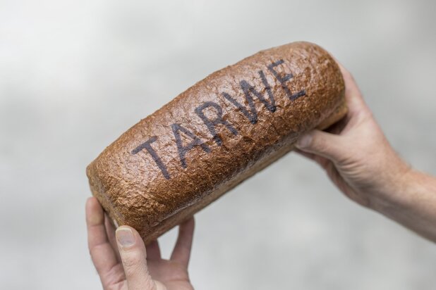 Wheat loaf with the word TARWE in baked RudinJet paste, held in two hands