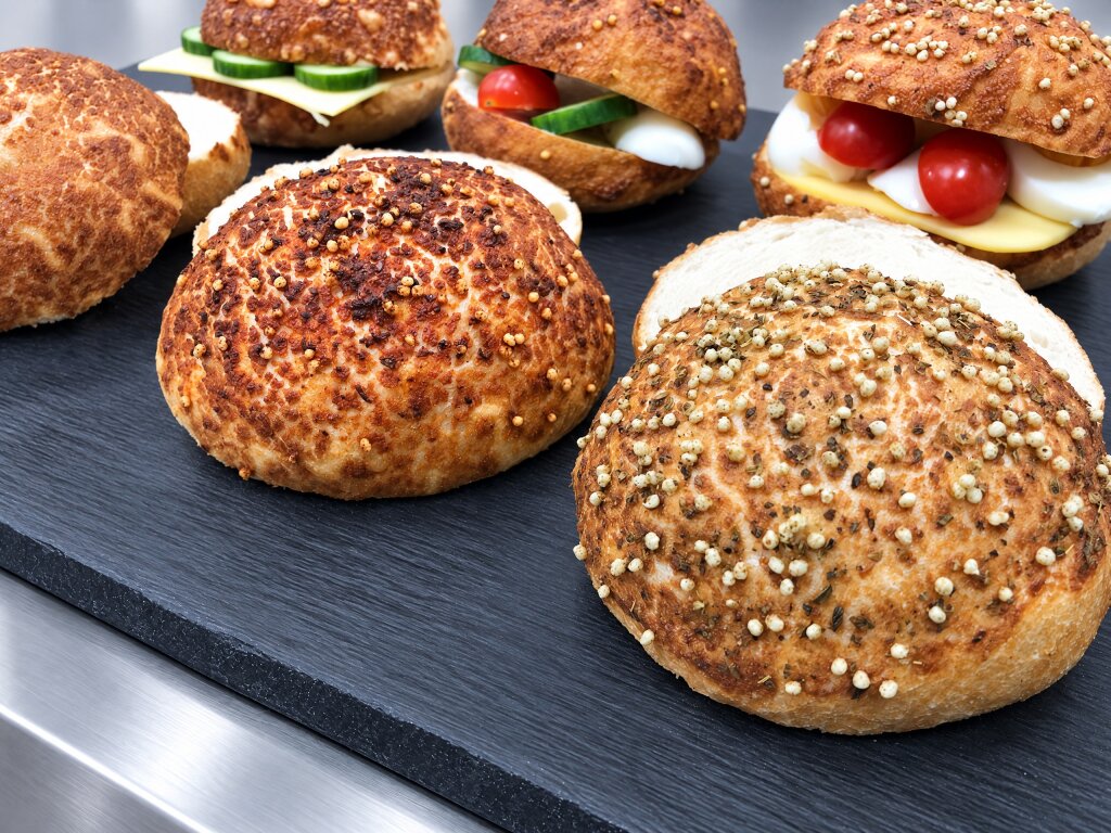 Close-up of burger buns with paprika and herb tiger topping on a slate board