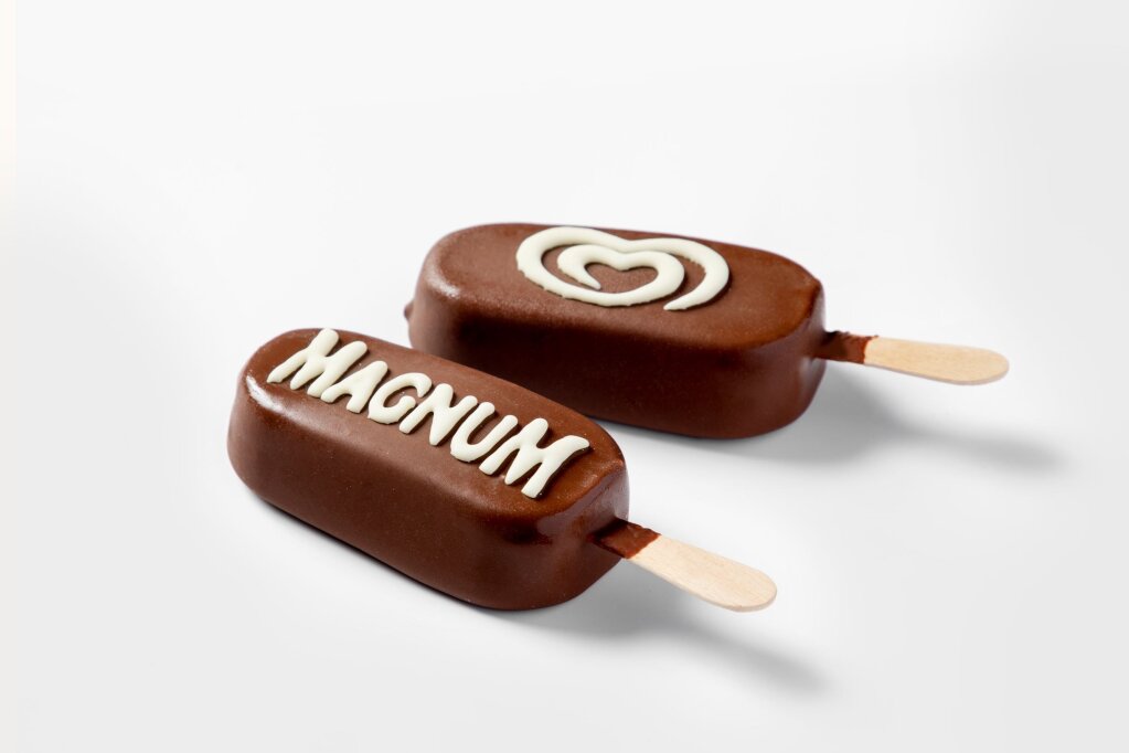 Two chocolate-coated ice cream bars on sticks, decorated with lettering and a heart-shaped swirl in white chocolate