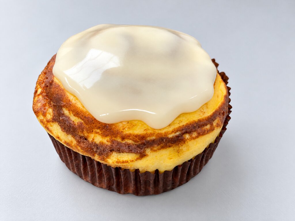 Baked cheesecake in a paper cup with a smooth white layer deposited on top, side view