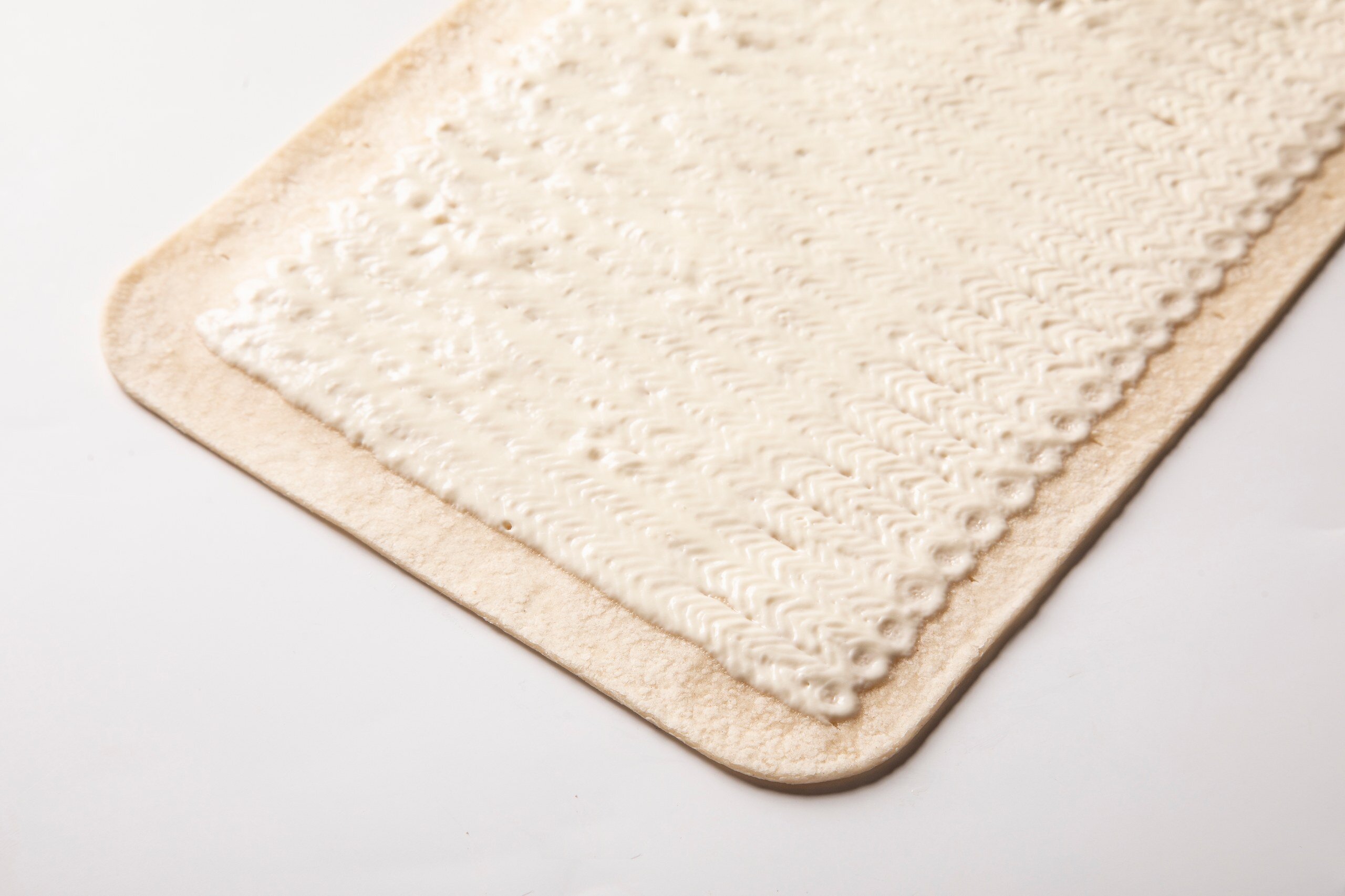Flatbread base with an even layer of cream deposited in fine ridged rows up to the edge
