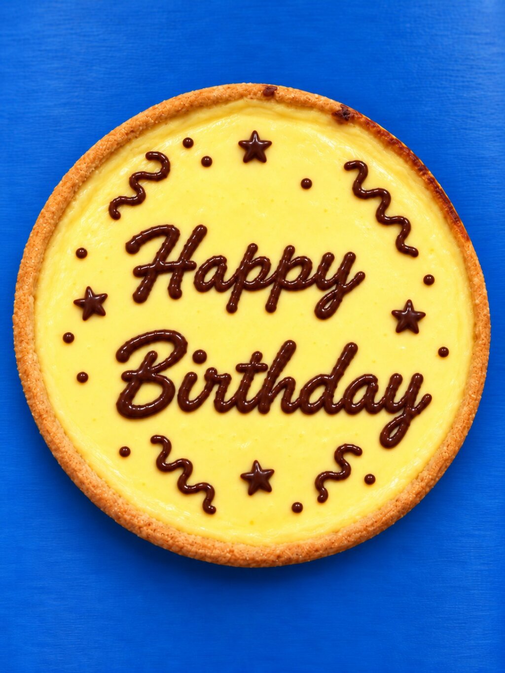 Round tart decorated with Happy Birthday lettering, stars and swirls in dark chocolate compound